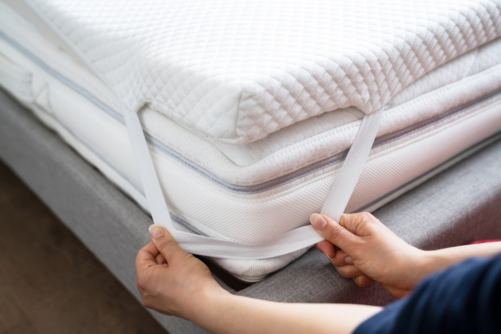 Mattress Topper Being Laid On Top Of The Bed